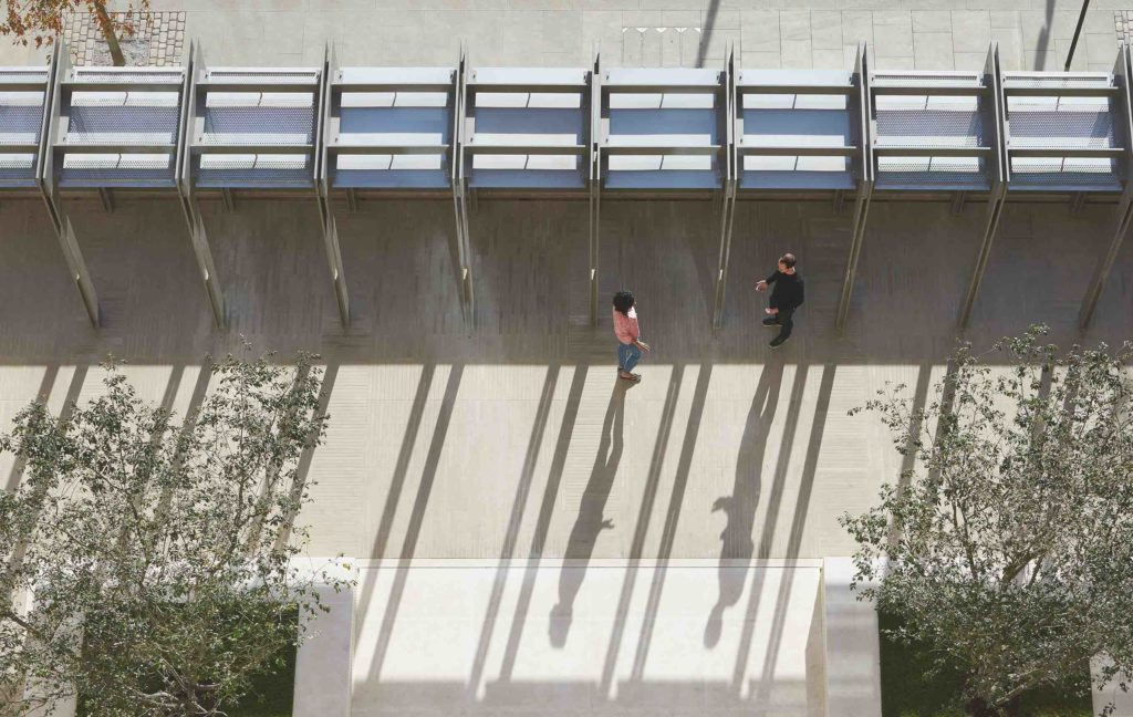 a view from above of two students speaking next to a wall.