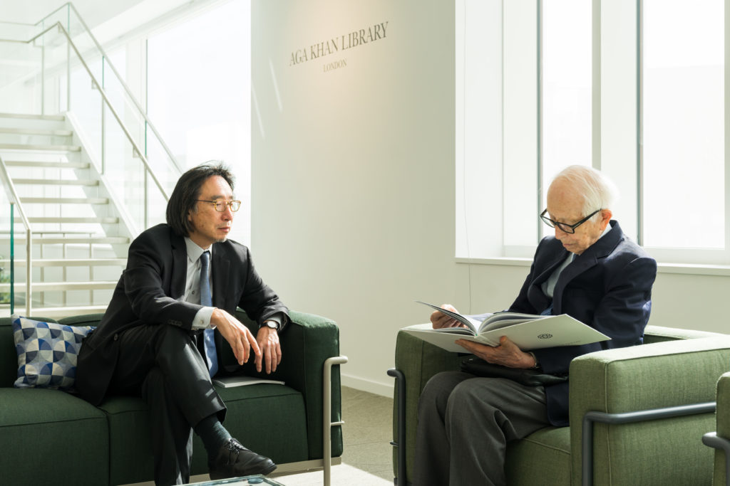 Two Japanese men in suits in discussion with one another,