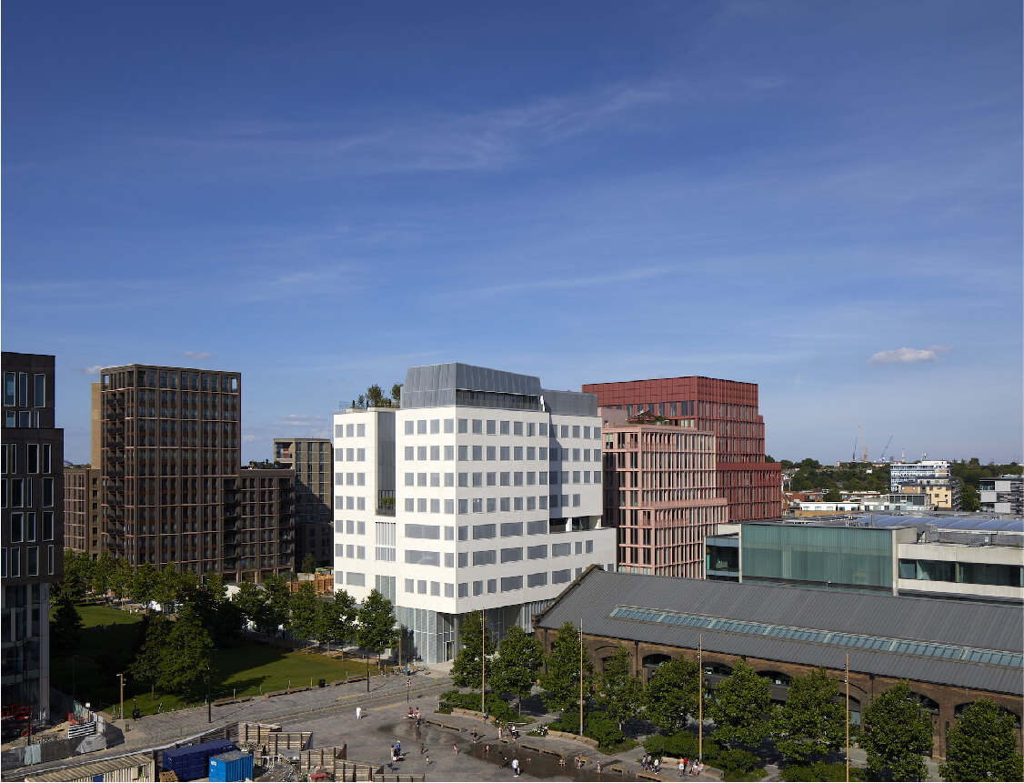A picture of the Aga Khan Centre, a white building surrounded by others against a dramatic blue sky.