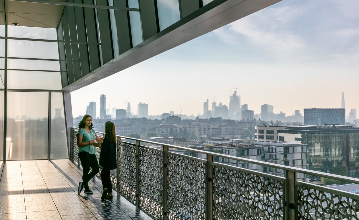 Two people on the Aga Khan Centre terrace with the London skyline behind them.
