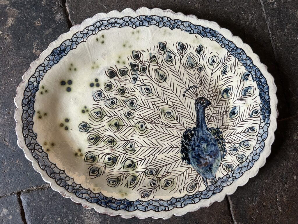 A plate with a painting of a peacock on it.